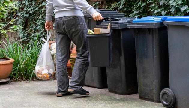Mann bringt seinen Müll zu Mülltonnen
