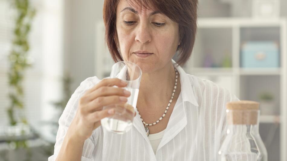 Frau schaut kritisch in ihr Glas