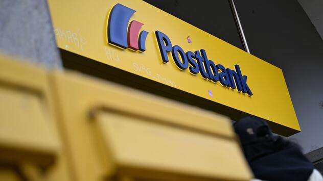 Der Schriftzug der Postbank am Eingang einer Filiale