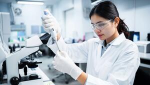 Eine Fachkraft für Medizintechnik schaut durch ein Mikroskop in einem Krankenhauslabor.