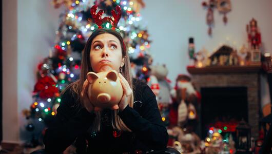 Frau hält an Weihnachten verzweifelt ein Sparschwein in der Hand