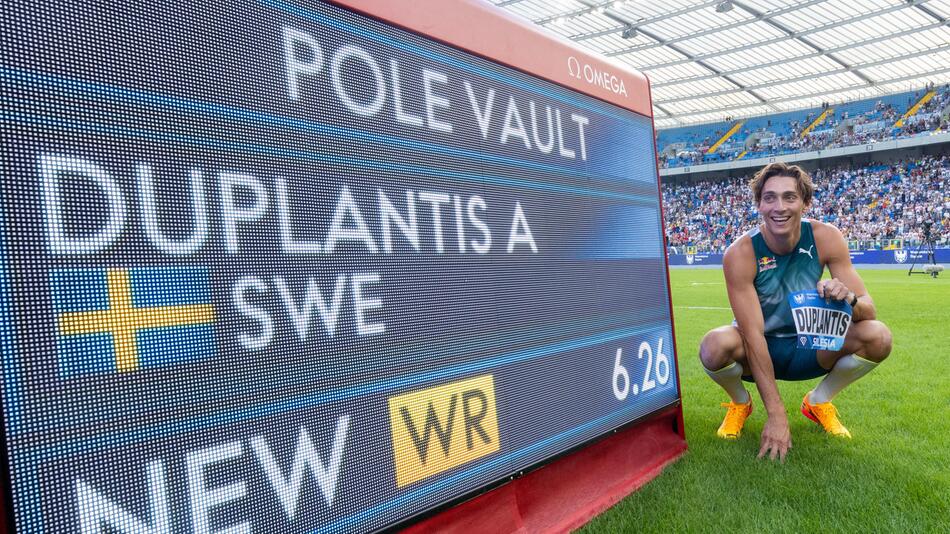 Armand Duplantis posiert stolz neben dem Bildschirm, der seinen neuen Weltrekord anzeigt.