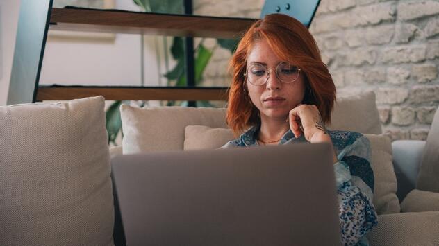 Frau schaut nachdenklich auf einen Laptop