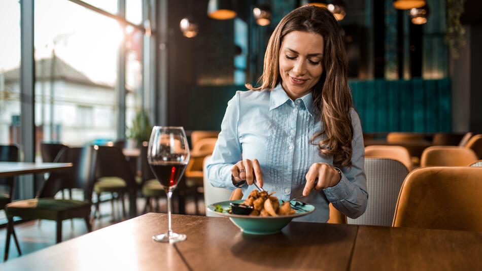 Junge Frau isst alleine und glücklich im Restaurant