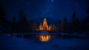 Leuchtender Weihnachtsbaum umgeben von Schnee in den Bergen