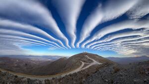 Dünne Wolken zeigen auf die Spitze eines Hügels.