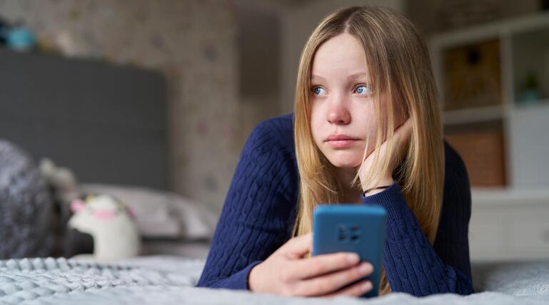 Unglückliches Mädchen mit Smartphone