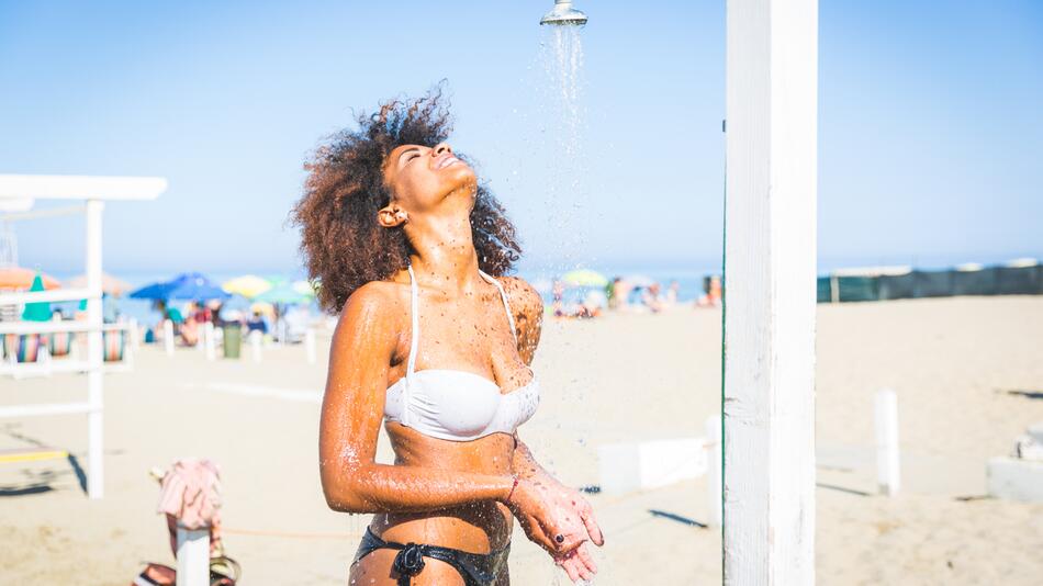Frau duscht am Strand