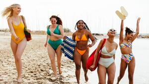 Freundinnen in Bademode laufen ausgelassen am Strand entlang