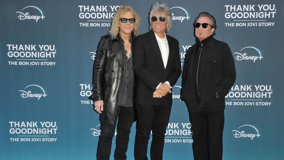 Jon Bon Jovi strahlt mit David Bryan (l.) und Tico Torres (r.) auf dem roten Teppich.