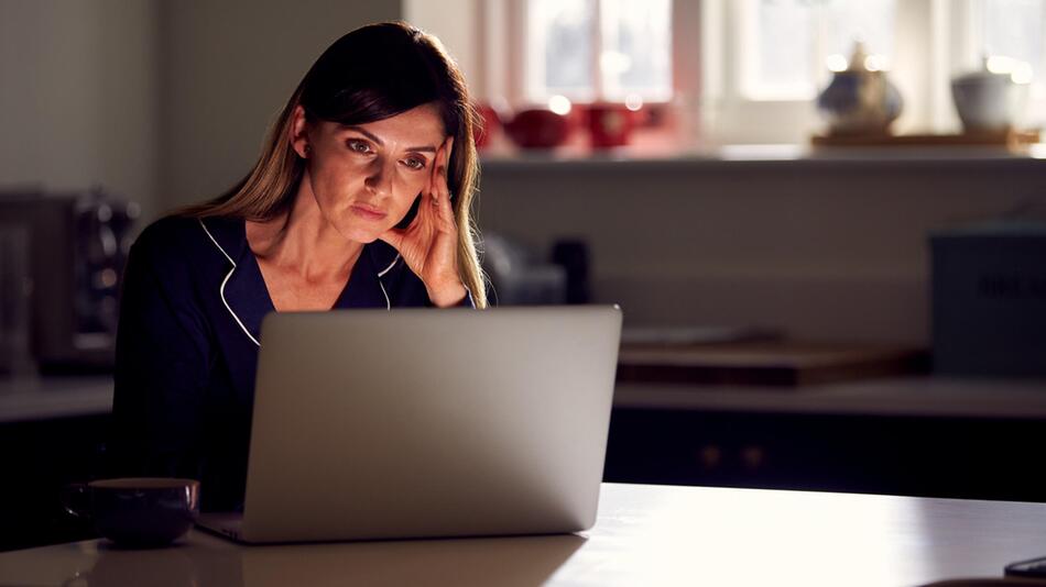 Frau sitzt unglücklich vor ihrem Laptop