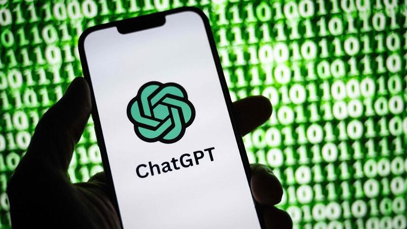 Eine Hand hält ein Handy mit dem Logo von ChatGPT in der Hand.