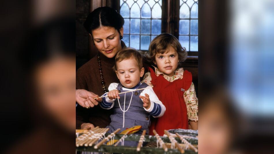 Königin Silvia, Prinz Carl Philip und Kronprinzessin Victoria 1980 beim Kerzenziehen.