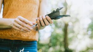 Eine Frau hält einige Federn in der Hand.