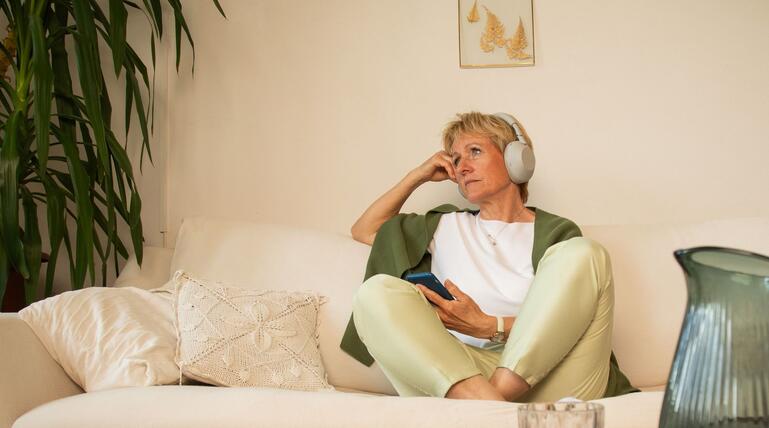 Eine Frau sitzt nachdenklich auf einem Sofa