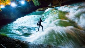 Ein Surfer reitet bei Nacht über die künstliche Welle des Eisbachs im Englischen Garten