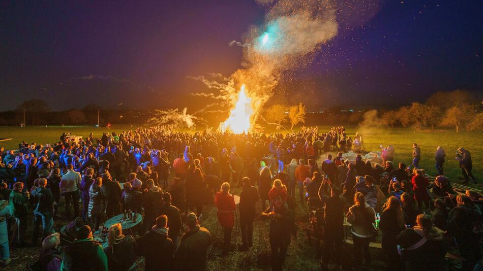 Menschen stehen um ein Osterfeuer