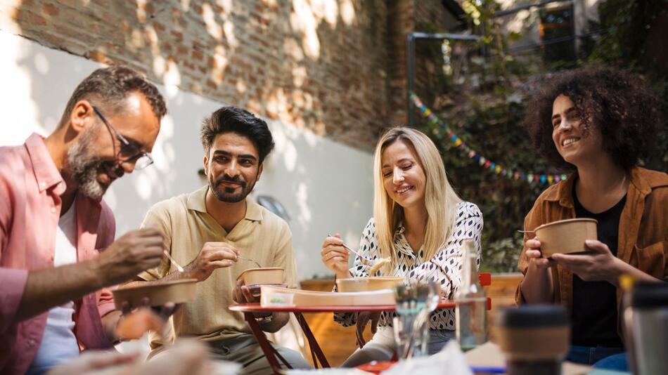 Freunde sitzen gemeinsam beim Essen