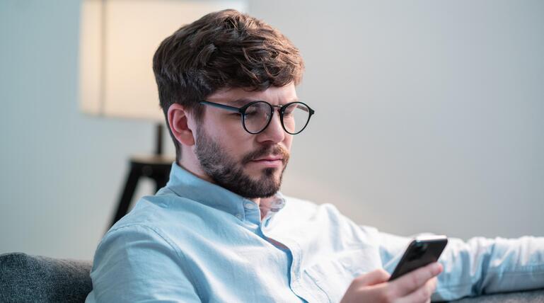 Junger Mann, der auf sein Handy schaut. 