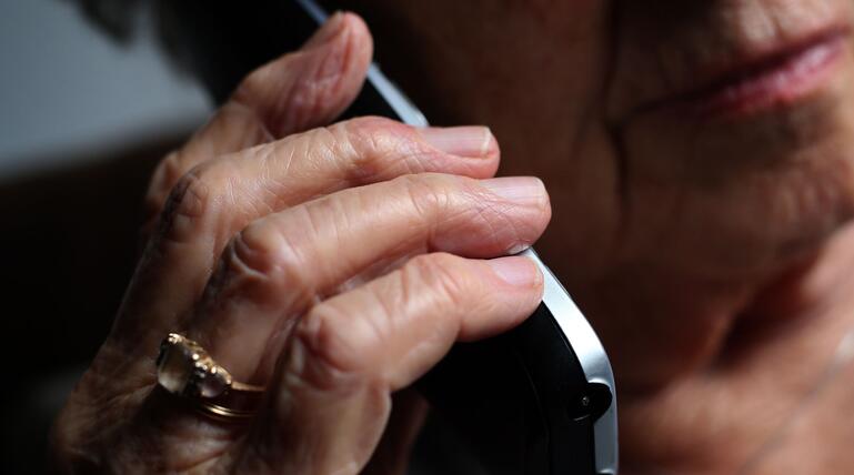 Seniorin telefoniert mit einem Festnetztelefon