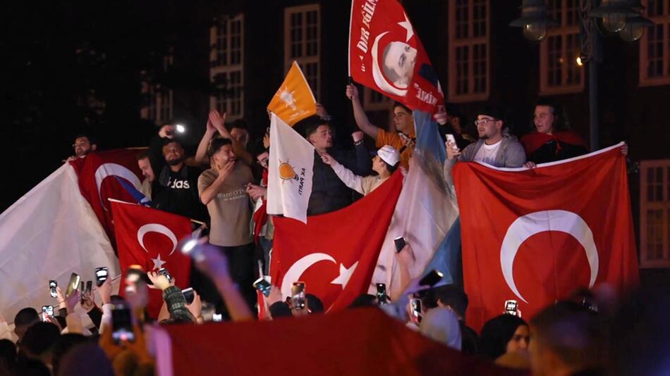 Mehrere Menschen zeigen türkische und andere Flaggen.