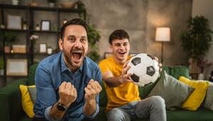 Zwei Männer mit Fußball jubeln vor dem Fernseher 