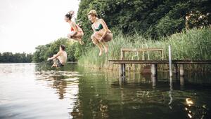 Drei junge Menschen springen in einen See