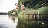 Drei junge Menschen springen in einen See