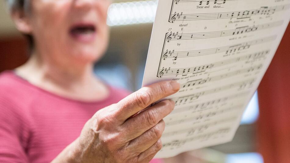 Eine Seniorin singt in einem Chor