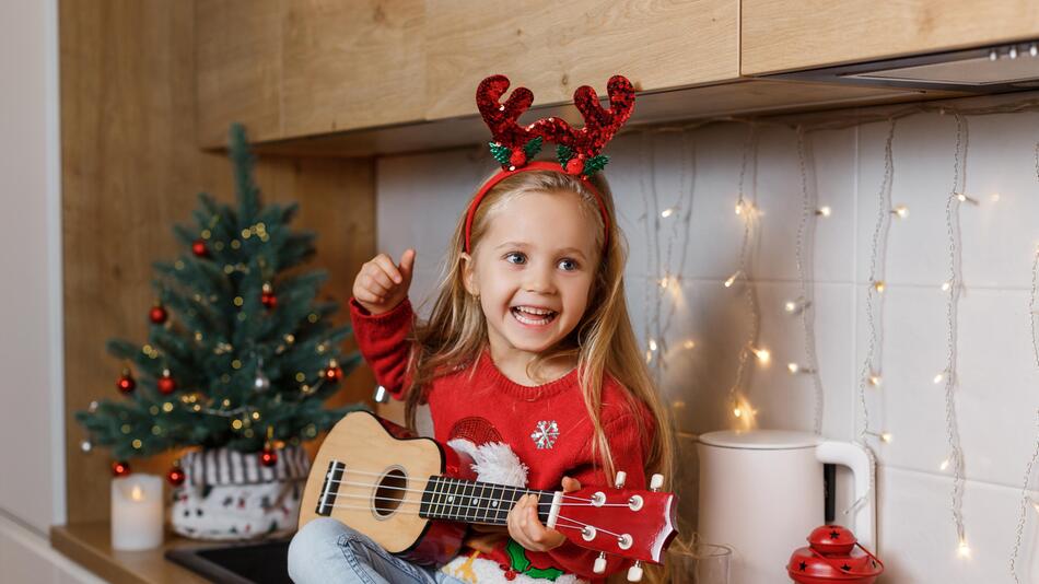 Mädchen spielt auf Ukulele im weihnachtlichen Ambiente