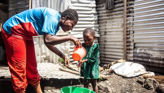 Eine Frau hilft einem Kind beim Händewaschen