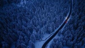 Ein Auto fährt durch den Winterwald im Erzgebirge