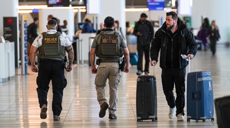 ICE-Agenten patrouillieren an einem Flughafen.