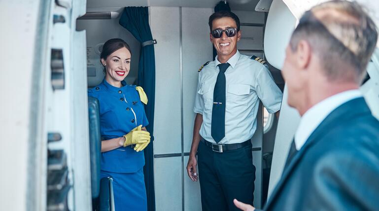 Flugbegleiterin und Pilot begrüßen Fluggast