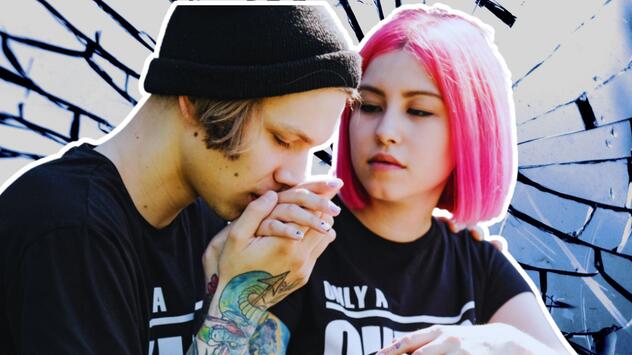 Junges Paar, er küsst ihre Hand. Sie hat pinke Haare. 