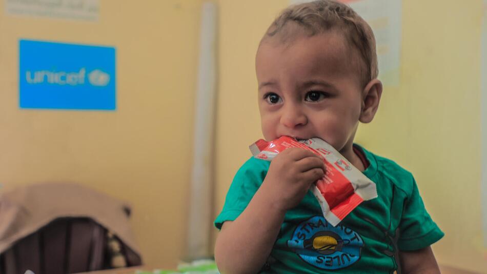 Foto vom kleinen Mohammed in Gaza, der an einer Packung Nahrungsmittelergänzung kaut.