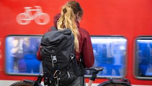 Eine Frau steht im Hauptbahnhof auf einem Bahnsteig mit einem Fahrrad vor einer S-Bahn