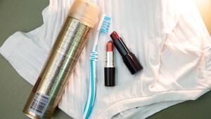 Lippenstift, Haarspray und eine Zahnbürste liegen auf einem Shirt