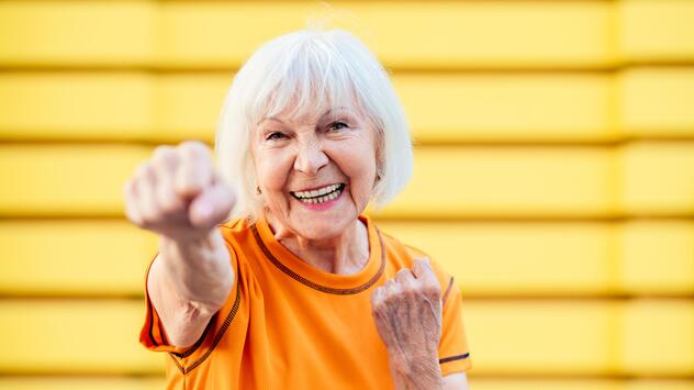 Seniorin, die gut gelaunt und sportlich aktiv ihre Faust nach vorne streckt