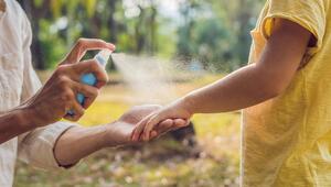 Mann sprüht Arm eines Kindes mit Insektenspray ein