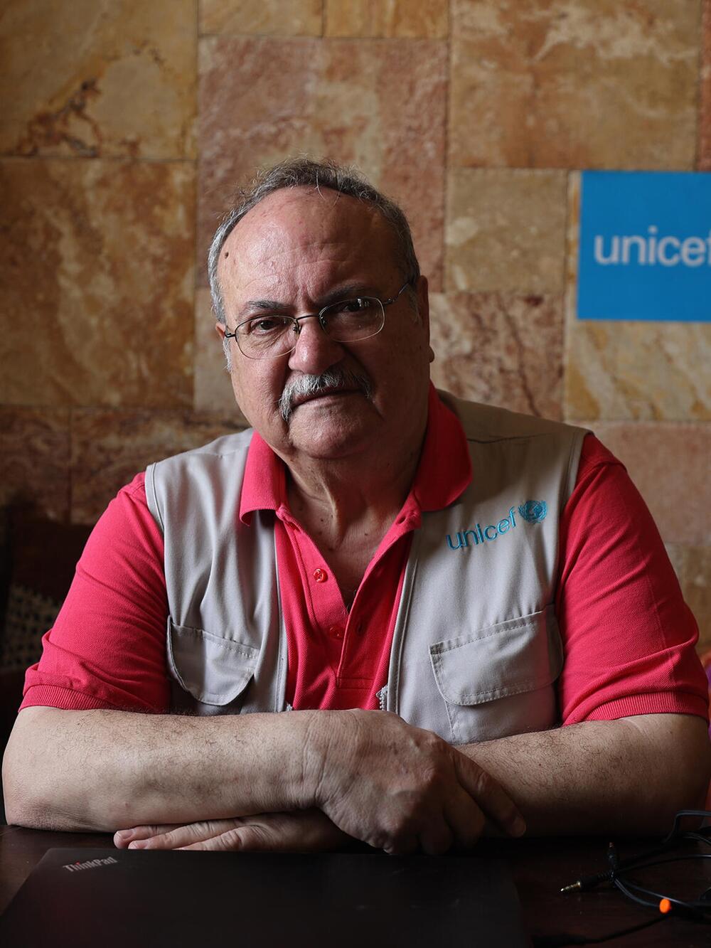 Ein Mann in einem roten T-Shirt und UNICEF-Weste blickt in die Kamera
