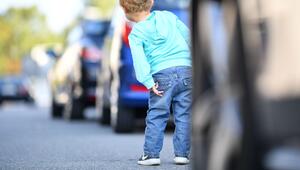 Kind steht zwischen parkenden Autos