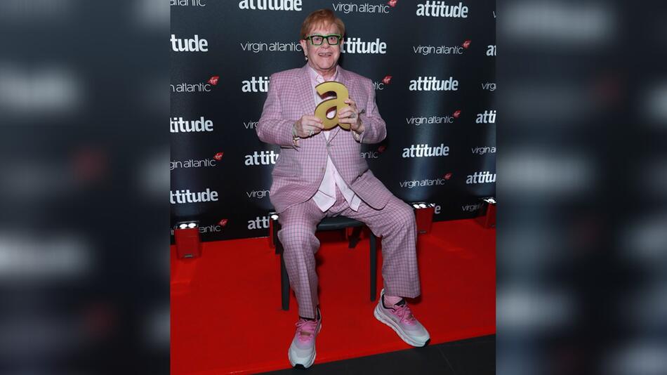 Elton John nahm zum Fotoshooting bei den Attitude Awards auf einem Stuhl Platz.