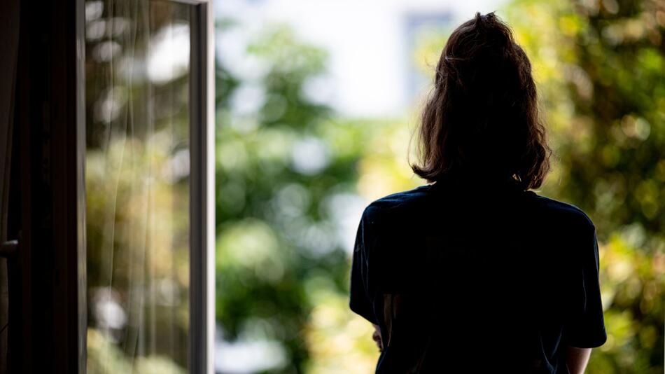 Eine Frau steht an einem offenen Fenster