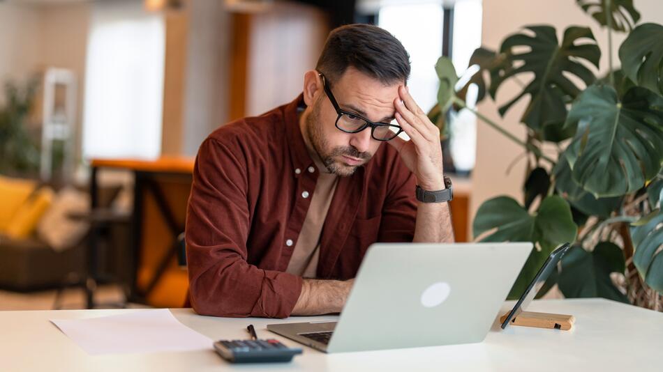 Mann sitzt verzweifelt am Laptop