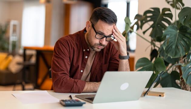 Mann sitzt verzweifelt am Laptop