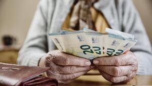 Eine alte Frau hält 20-Euro-Scheine in der Hand. Daneben liegt ein Portemonnaie auf dem Tisch.