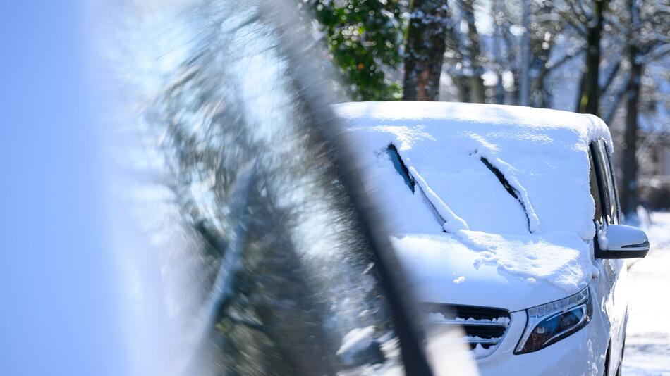 Schnee liegt auf den parkenden Autos.