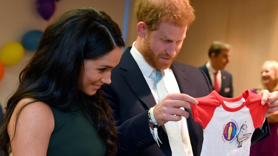 Harry und Meghan betrachten sich Kleinkinderkleidung