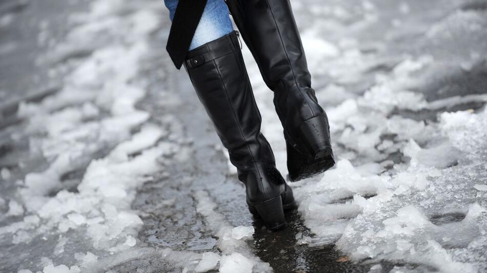 Frau läuft durch nassen Schneematsch